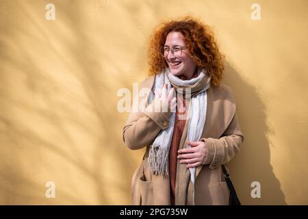 Natürliches Porträt einer lächelnden weissen Ingwerfrau mit Sommersprossen und Locken. Stockfoto