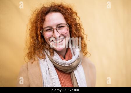 Natürliches Porträt einer lächelnden weissen Ingwerfrau mit Sommersprossen und Locken. Stockfoto