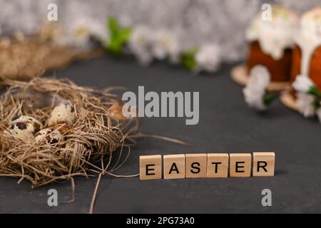 Osteraufschrift auf Holztafeln. Wachteleier im Nest. Stockfoto