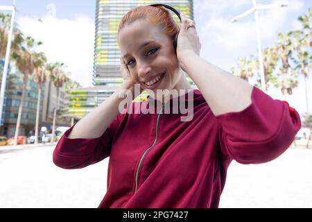 Nahaufnahme einer jungen rothaarigen Frau mit Kopfhörern Stockfoto