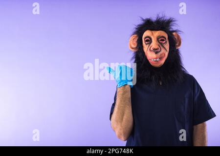 Verkleidete Person in einer Affenmaske und Arztkostüm, zeigt mit dem Finger zur Seite, auf lila Hintergrund. AFFENPOCKEN, Pandemie, Virus, Epidemie Stockfoto