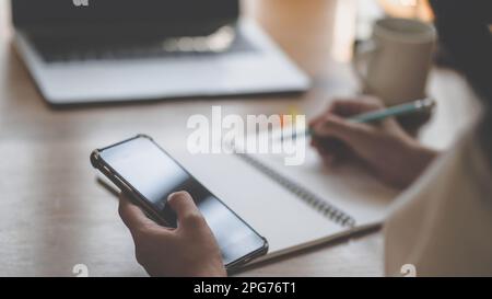 Zugeschnittene Handaufnahme mit Smartphone, Laptop und Taschenrechner mit Karte auf dem Schreibtisch, Geschäftskonzepte. Stockfoto