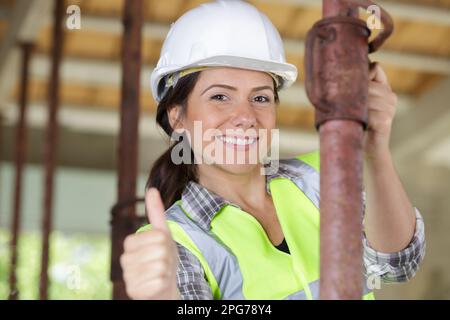 Weibliche Lohnarbeiterin zeigt Daumen-hoch Stockfoto