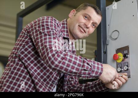 Mann, der die Maschine in einer Fabrik bedient Stockfoto