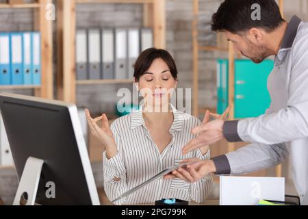 Eine ruhige, attraktive Geschäftsfrau, die Yoga bei der Arbeit praktiziert Stockfoto