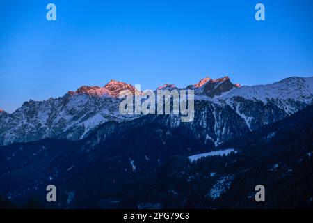 Sonnenuntergang, mit Gipfeln wie Muot la Seila (2.387 m) und Piz Sursass (2.910 m) in Orange/Pink, aus Guarda, Niederengadin, Schweiz Stockfoto
