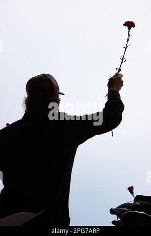 Ein Mann mit Silhouette steht im Vordergrund und hält eine Blume in der rechten Hand Stockfoto