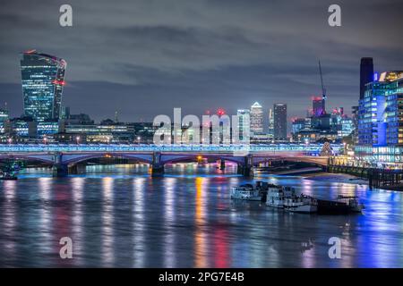 Eine nächtliche Stadtlandschaft von London mit Blackfriars Bridge und der Themse mit den Gebäuden der Stadt London und den Docklands dahinter. Stockfoto