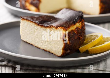 Nahaufnahme eines Stücks verbrannten San Sebastian Käsekuchen auf einem Teller auf dem Tisch. Horizontal Stockfoto