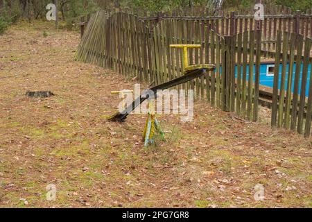 Eine alte, verfallene Kinderschaukel in einem verlassenen und vergessenen Ferienresort im Wald. Urbex. Stockfoto