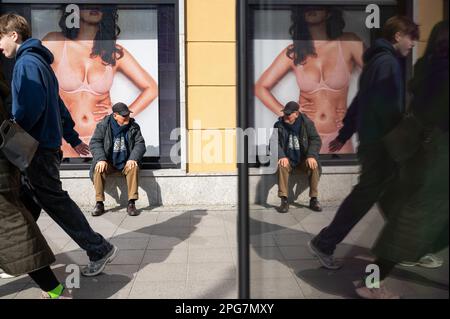 18.03.2023, Berlin, Deutschland, Europa - Ein Mann wird reflektiert, wenn er vor einem Schaufenster sitzt und auf dem Kurfürstendamm in City West Werbung macht. Stockfoto