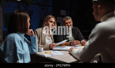 Selbstbewusste Geschäftsleute, die gemeinsam Ideen sammeln und im Team an einem neuen Projekt im Büro arbeiten. Nachtarbeit Stockfoto