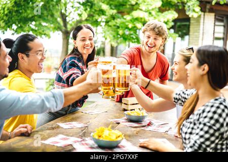 Junge, glückliche Freunde trinken und toasten Bier in der Brauerei Bar Farm House Patio - Getränke Lifestyle Konzept mit echten Jungs und Mädchen, die Spaß haben Stockfoto