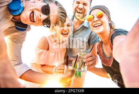 Trendige Personengruppe Selfie beim Spring Break Festival mit ausgefallenen Cocktails bei Sonnenuntergang - Sommerfreude und Freundschaftskonzept mit jungen Freunden Stockfoto