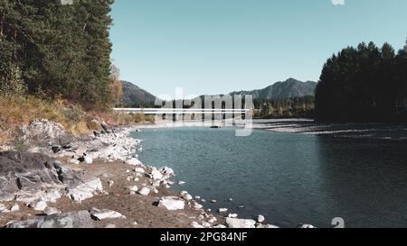 Ein ausgetrockneter Kanal des Flusses Katun mit einer Brücke über den Fluss an einem hellen Tag in Altai im Herbst. Stockfoto