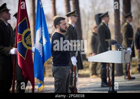 Moschun, Ukraine. 21. März 2023. Der ukrainische Präsident Volodymyr Zelenskyy steht für die Nationalhymne während einer Zeremonie an der Gedenkstätte der Engel des Sieges am 21. März 2023 in Moschun, Oblast Kiew, Ukraine. Kredit: Pool Photo/Pressestelle Des Ukrainischen Präsidenten/Alamy Live News Stockfoto