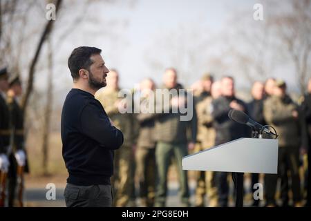 Moschun, Ukraine. 21. März 2023. Der ukrainische Präsident Volodymyr Zelenskyy steht für die Nationalhymne während einer Zeremonie an der Gedenkstätte der Engel des Sieges am 21. März 2023 in Moschun, Oblast Kiew, Ukraine. Kredit: Pool Photo/Pressestelle Des Ukrainischen Präsidenten/Alamy Live News Stockfoto