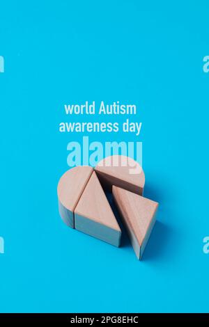 Nahaufnahme einiger Bausteine, die ein Herz bilden, und des Text World Autismus Awareness Day vor blauem Hintergrund Stockfoto