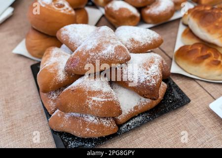 Muffins mit Zuckerpulver in Silikonform. Süße Kuchen mit Puderzucker auf dem Tisch oder an der Theke im Geschäft. Stockfoto