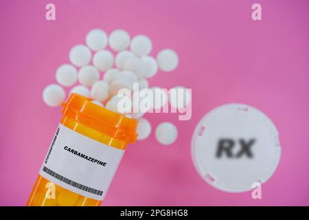 Carbamazepin Rx-Arzneimittel-Pillen in Plazentaglaschen mit Tabletten. Tabletten, die aus dem gelben Behälter auf rosa Hintergrund verschüttet werden. Stockfoto