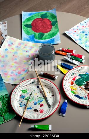 Fotografieren Sie viele Farben in einer Röhre, Blätter zum Malen, Pinsel auf einem runden Tisch Stockfoto