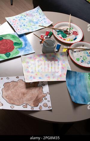 Ein Foto von vielen Blättern mit Zeichnungen und bunten Farben mit Pinseln auf dem Tisch Stockfoto