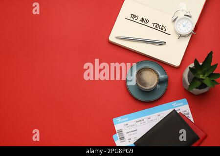 Flache Laienzusammenstellung mit Reisetipps in Notizbuch, Reisepässen, Tickets und einer Tasse Kaffee auf rotem Hintergrund. Platz für Text Stockfoto