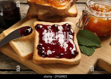 Köstliche Toasts mit Marmelade auf Holzbrett, Nahaufnahme Stockfoto