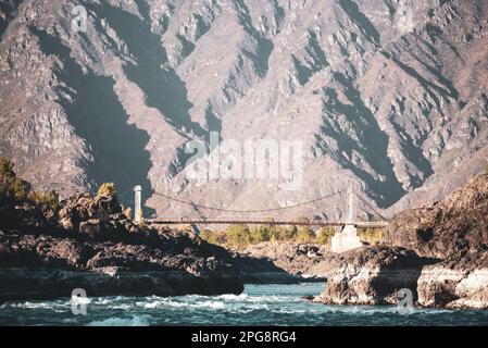Oroktoysky-Brücke über den Bergfluss Katun mit Stromschnellen in der Schlucht aus Felsen vor dem Hintergrund der großen Berge in Altai. Stockfoto