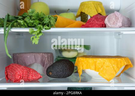 Offener Kühlschrank mit vielen verschiedenen Produkten, verpackt in Bienenwachs-Lebensmittelverpackungen Stockfoto