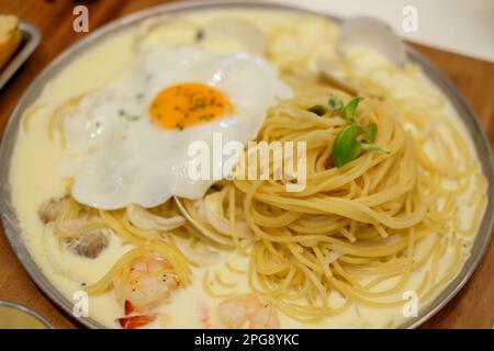 Spaghetti Seafood Cream Sauce mit Spiegelei, serviert auf dem Teller Stockfoto