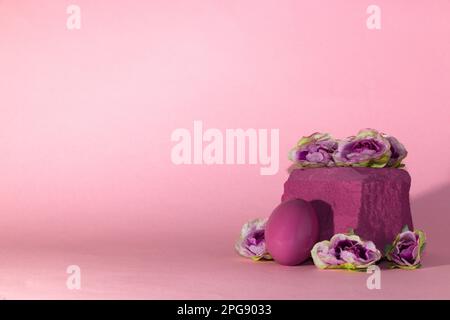 Pinkfarbenes Osterei auf pinkem Stein mit Blumen, pinkfarbenem Hintergrund, kreatives Weihnachtsdesign Stockfoto
