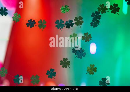 Grüne, glitzernde Shamrocks, hausgemachte Girlande auf farbenfrohem, verschwommenem Hintergrund. Happy St. Patricks-Day-Konzept, Bannerdesign, selektiver Fokus Stockfoto