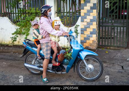 Eine Mutter trägt ihre beiden jungen Kinder auf einem Honda Wave Motorradroller in Buon Jun, Lien Son, Vietnam. Stockfoto