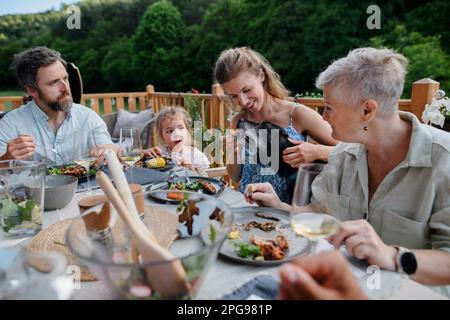 Eine Familie mehrerer Generationen isst auf einer Barbecue-Party zu Abend. Stockfoto