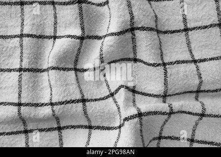 Klassisches Küchenhandtuch mit Karomuster in Schwarz und Weiß. Zerknitterter Textilhintergrund mit sichtbarem Gewebe- und Fadendetail. Ideal für Web- und Druckanwendungen Stockfoto