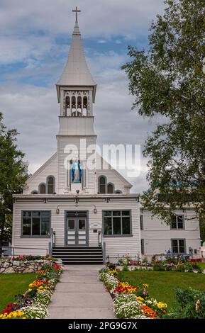 Fairbanks, Alaska, USA - 27. Juli 2011: Portrait der weißen Holzfassade Immaculate Conception Katholische Kathedrale in ihrem Blumengarten mit gee Stockfoto