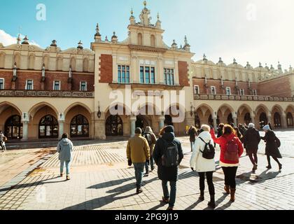 Krakau, Polen - 6. märz 2023: Reiseleiter mit Reisegruppe auf dem Hauptplatz in Krakau. Kostenlose Touristenwanderungen mit Einheimischen. Einzigartiges Erlebnis in New Cit Stockfoto