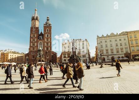 Krakau, Polen - 6. märz 2023: Gemeinsamer Spaziergang mit Reiseleiter und Gruppe auf dem Hauptplatz in Krakau. Kostenlose Touristenwanderungen mit Einheimischen. St. Mary Basili Stockfoto