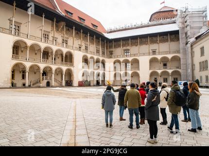 Krakau, Polen - 6. märz 2023: Reiseleiter mit Reisegruppe im Königlichen Schlosshof Wawel in Krakau. Kostenlose Touristenwanderungen mit Einheimischen. Einzigartiges Erlebnis Stockfoto