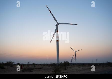 Licht vor der Dämmerung am Wüstenhimmel mit Strom erzeugenden Windmühlen, die umweltfreundliche Energie für den Verbrauch erzeugen. Stockfoto