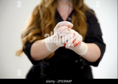 Hand mit Stoppschild in Latexhandschuh mit Blut. Die blutige Hand isolierte sich auf weißem Hintergrund. Sozialgewalt und Unsicherheitsbegriff. Teil des Sets. Hochwertiges Foto Stockfoto