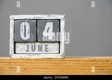 Kalender für Juni 04 aus Holzwürfeln, die auf einem Regal auf grauem Hintergrund stehen. Mit einem leeren Platz für Ihren Text Stockfoto