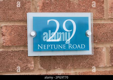 Tür Nummer 29 und Straßenname Neptune Road in Weiß auf blauem Hintergrund, an einer Ziegelwand montiert. Stockfoto