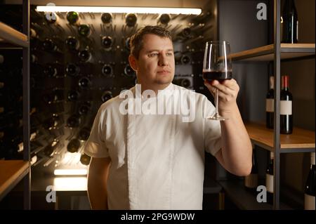 Erfolgreicher männlicher Sommelier, der den Geschmack verkostet und die Weinqualität prüft Stockfoto