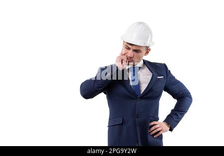 Ein gutaussehender Mann in Anzug und Helm denkt darüber nach, ein Problem zu lösen. Konzept im Studio auf weißem Hintergrund. Stockfoto