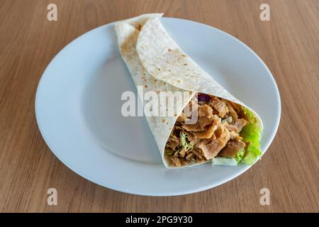 Hähnchenfleisch-Döner Kebab und frisches Gemüse in Pita-Brötchen auf einem Teller. Durum Chicken Döner Kebab Stockfoto