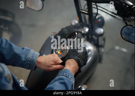 Nahaufnahme der Biker-Hand mit Lederhandschuhen über dem Motorradtank Stockfoto