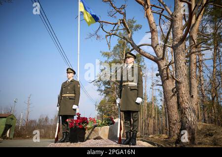 Moschun, Ukraine. 21. März 2023. Ehrengäste stehen am 21. März 2023 in Moschun, Oblast Kiew, Ukraine, an der neu enthüllten Denkmälerstätte der Engel des Sieges. Kredit: Pool Photo/Pressestelle Des Ukrainischen Präsidenten/Alamy Live News Stockfoto