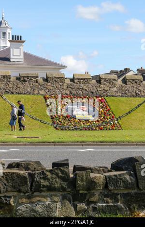 Spring Antrim zwei Leute Mann und Frau gehen vorbei am Blumenbeet zu Ehren des Snooker-Spielers Mark Allen, der aus der Stadt kommt. Stockfoto